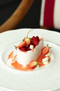 Elegant French dessert garnished with fresh strawberries, captured in a stylish restaurant setting.